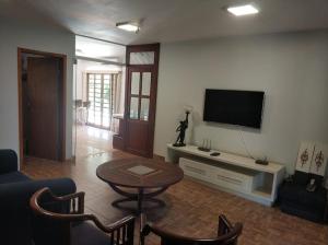 伊瓜苏Pousada Falls Park的客厅配有电视和桌椅