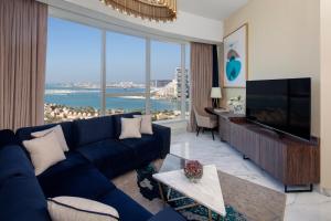 迪拜Avani Plus Palm View Dubai Hotel & Suites的客厅设有蓝色的沙发和大窗户