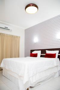 马拉巴圣本托酒店的卧室配有带红色枕头的大型白色床