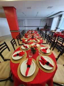 马拉巴圣本托酒店的一张长桌,桌子上摆放红色的桌子,椅子上摆放着盘子和餐巾