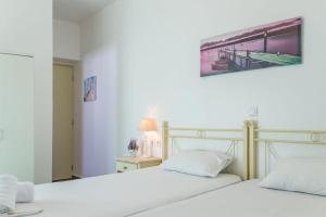 安提帕罗斯岛Limani的卧室内配有两张白色的床,墙上挂着一幅画