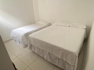 马拉戈日Mellim Residence的小客房内的两张床,配有白色床单