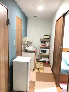 大阪Shoyaya Hostel的一间设有门的房间,可通往一个配有微波炉的房间