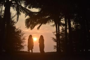 马拉利库兰Xandari Pearl Beach Resort的两个女人站在日落前