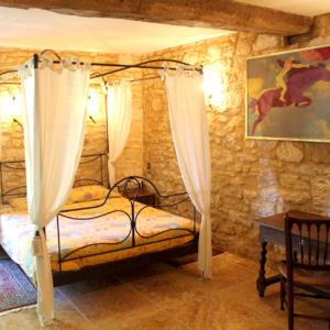 Saint-CybranetMaison de 2 chambres avec piscine partagee jardin amenage et wifi a Saint Cybranet的一间卧室配有一张带窗帘和桌子的床