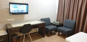 阿罗士打Hotel Samila的客房设有桌椅和墙上的电视。
