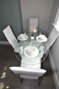 特伦特河畔斯托克Townhouse @ Penkhull New Road Stoke的一张玻璃桌,上面有两把白色的椅子和盘子