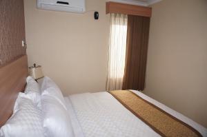 日惹萨法度假屋的一间卧室配有一张带白色床单的床和一扇窗户。