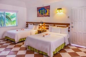 拉纳韦贝Decameron Club Caribbean Runaway Bay, Ramada All-Inclusive Resort的一间卧室配有两张带白色床单的床