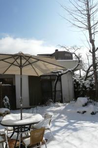富士河口湖K's House MtFuji -ケイズハウスMt富士- Travelers Hostel- Lake Kawaguchiko的雪地中的桌椅和雨伞