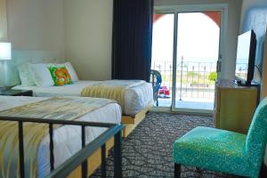 五月岬郡长春花旅馆的酒店客房设有两张床、一把椅子和阳台