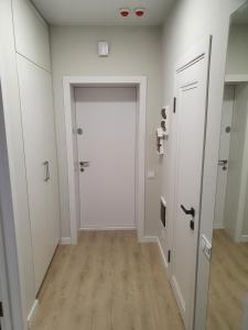 罗夫诺Prestige Apartments的一条带白色墙壁和白色门的走廊