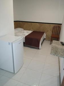 瓜拉派瑞Pousada Solar da Praia的小房间设有一张床和一台冰箱