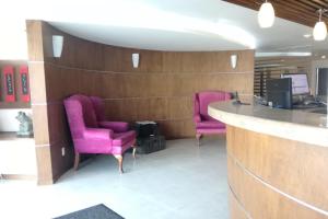帕丘卡德索托Mision Express Pachuca的大堂设有两把紫色椅子和一个柜台