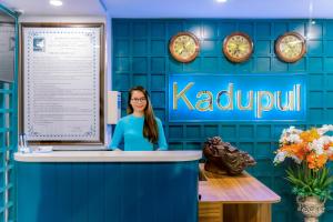 归仁KADUPUL HOTEL的一名妇女站在一个库拉的专区办公室的柜台上