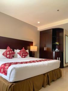 宿务阿尔帕城市套房酒店的一间卧室配有一张带红色枕头的大床