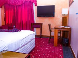 达喀尔Hotel Fleur De Lys Almadies的酒店客房设有床、桌子和电视。