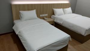 马六甲Maple Boutique Hotel的酒店客房内的两张床,配有白色床单
