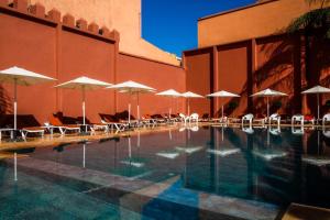 马拉喀什戴文酒店＆马拉喀什Spa的一个带遮阳伞和椅子的游泳池以及一座建筑