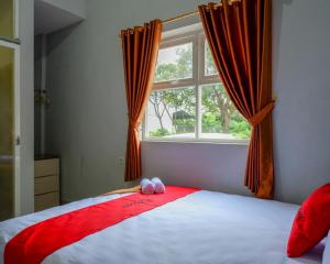 AlastuwoRedDoorz @ City Park Medoho Semarang的卧室配有红色和白色的床,设有窗户