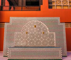 马拉喀什戴文酒店＆马拉喀什Spa的坐在橙色墙前的白色长凳