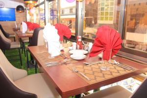 纳库鲁Vickmark Hotel的餐厅的桌子,有红色的餐巾和餐具