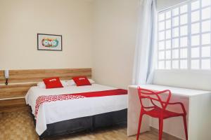 巴西利亚OYO Hotel Brisa Tropical, Brasília的一间卧室配有一张床和一张红色椅子