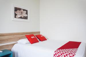 巴西利亚OYO Hotel Brisa Tropical, Brasília的一间卧室配有红色和白色枕头的床