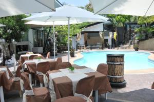 安蒂波洛佳期美食度假酒店的池畔餐厅,配有桌子和遮阳伞