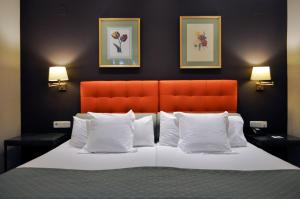 塞维利亚圣吉尔酒店的一间卧室配有一张带橙色床头板和白色枕头的床。