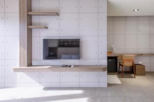 马公尖尖民宿的一间厨房,拥有白色的瓷砖墙壁和一台大电视
