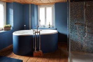 CuragliaNostalgie Bed & Breakfast Chrämerhus的蓝色的浴室设有浴缸和淋浴。