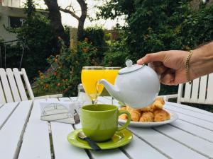 埃斯特角城圣雷莫蓬酒店 的把茶壶和茶杯放在桌子上的人