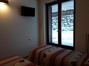 圣卡特琳娜瓦尔夫Apartments "STELLA ALPINA"的一间卧室配有床,外面设有一扇雪窗