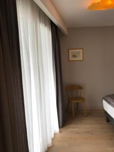 安锡LA COSTIERE DU LAC - ANNECY - Vieille ville, Plage, Garage的卧室设有窗户、白色窗帘和椅子