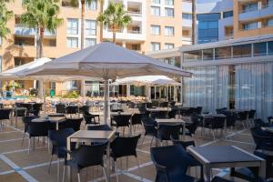 滨海罗克塔斯Hotel Neptuno by ON GROUP的一个带桌椅和遮阳伞的庭院