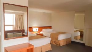 Puerto La CruzHotel Cristina Suites的酒店客房,设有两张床和镜子
