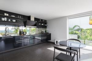 茶云莱海滩Villa Sasipimon - Panoramic Duplex Studio的厨房配有黑色橱柜和玻璃桌
