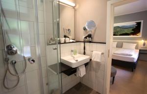 特里费尔斯山麓安韦勒Jugendstilhotel Trifels的一间带水槽和淋浴的浴室以及一张床