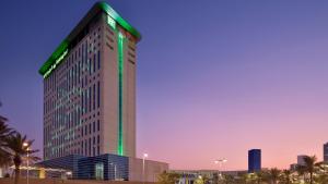 迪拜Holiday Inn & Suites - Dubai Festival City Mall, an IHG Hotel的一座高大的建筑,上面有一条绿条