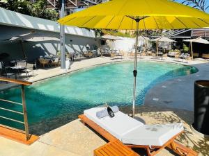 达喀尔BOMA LifeStyle Hotel的游泳池配有黄色遮阳伞和带电话的躺椅