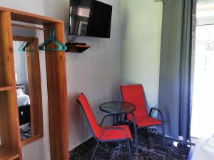 萨玛拉Tuki Tuki Lodge的一间设有两把椅子、一张桌子和一台电视的房间