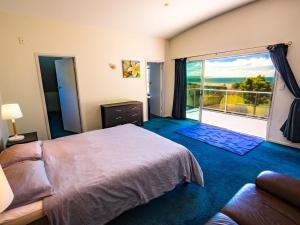 TasmanLa Casa Al Mare - Golden Bay Beach House的一间卧室设有一张大床和一个大窗户