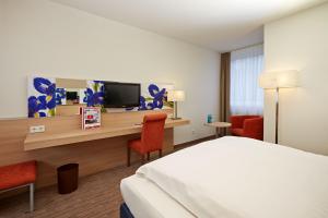 下恩豪森尼登豪森威斯巴登H+酒店的酒店客房设有一张床和一张带电视的书桌。