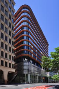 悉尼Little National Hotel Sydney的一座高大的建筑,前面有标志
