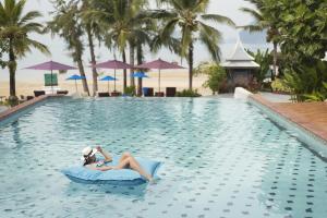 塔可克海滩Anyavee Tubkaek Beach Resort- SHA Plus的一位女士躺在度假村的游泳池里木筏上