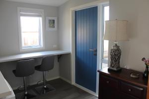 皇后镇Blue Skies Guest Accommodation的一间设有蓝色门、一张桌子和椅子的房间