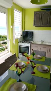 圣安娜Appartement d'une chambre avec vue sur la mer piscine partagee et balcon amenage a Sainte Anne a 1 km de la plage的厨房拥有绿色的墙壁,配有一张桌子和两把椅子