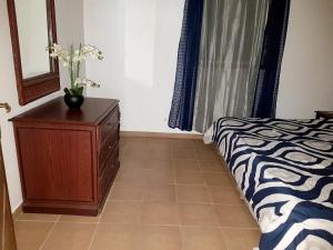 Happy BayOne bedroom appartement with furnished garden and wifi at La Savane 2 km away from the beach的一间卧室配有床和鲜花梳妆台。