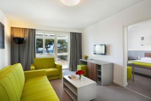 弗尔萨尔Maistra Select Pineta Hotel的客厅配有黄色的沙发和床。
